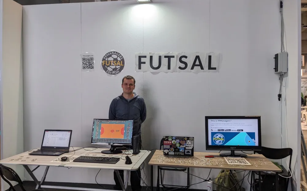 Picture of my stand at the Freizeit/Tempo libero fair in Bolzano, Italy. There are 2 tables with 2 displays and a laptop where my game 99Managers Futsal Edition is running and I stand behind the table.